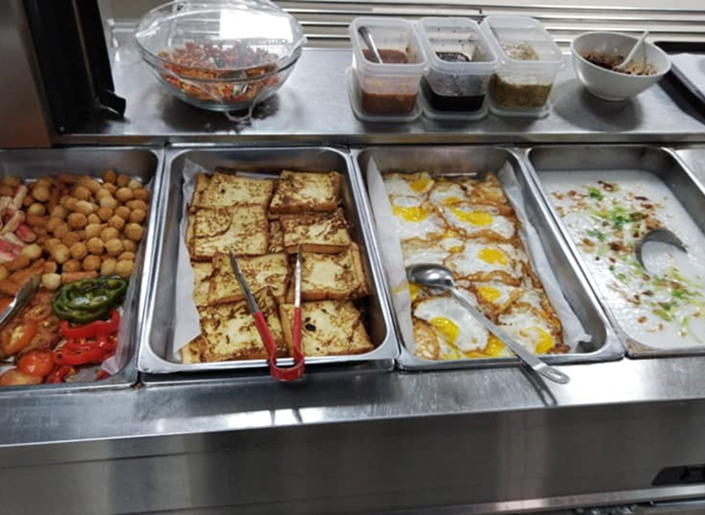 Cafeteria food trays with prepared breakfast dishes