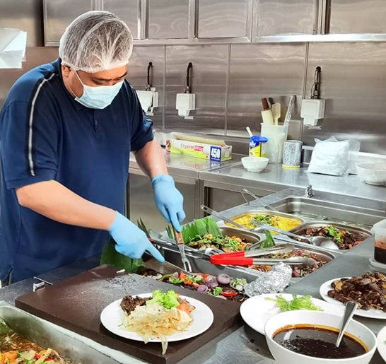 Catering staff plating meals in a commercial kitchen